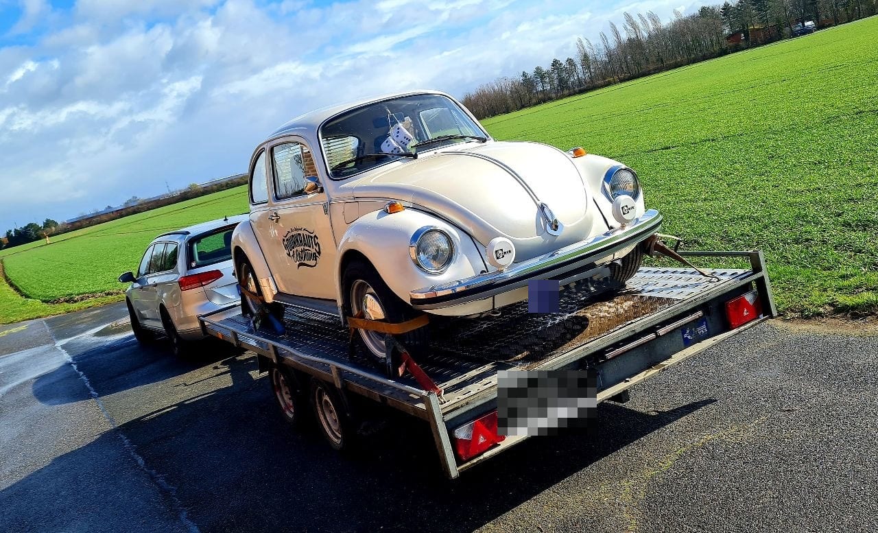 Weißer VW Käfer auf einem Autotransport-Anhänger